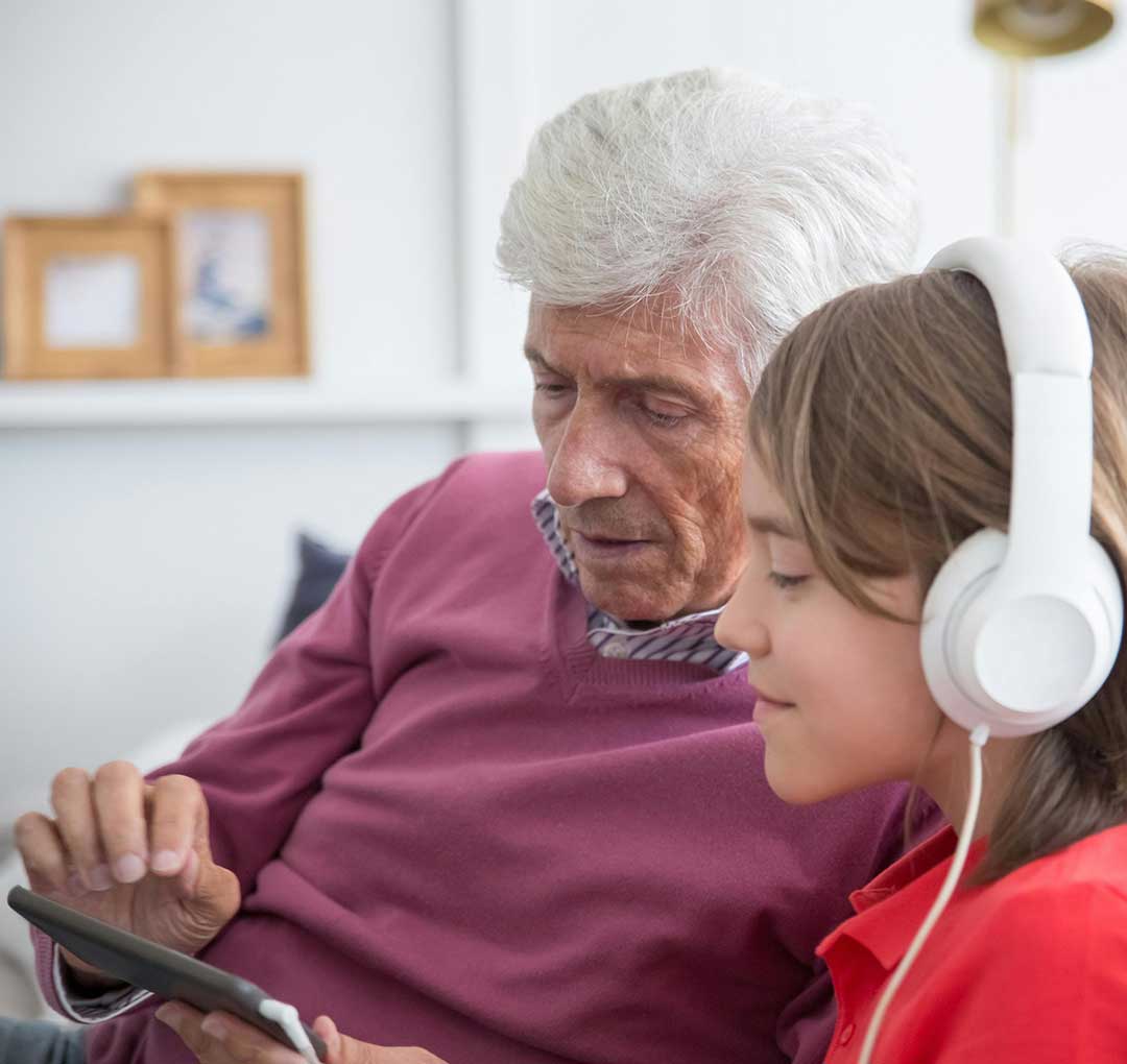 Grandfather and grandson using an AAC device together, demonstrating specialized communication therapy support.