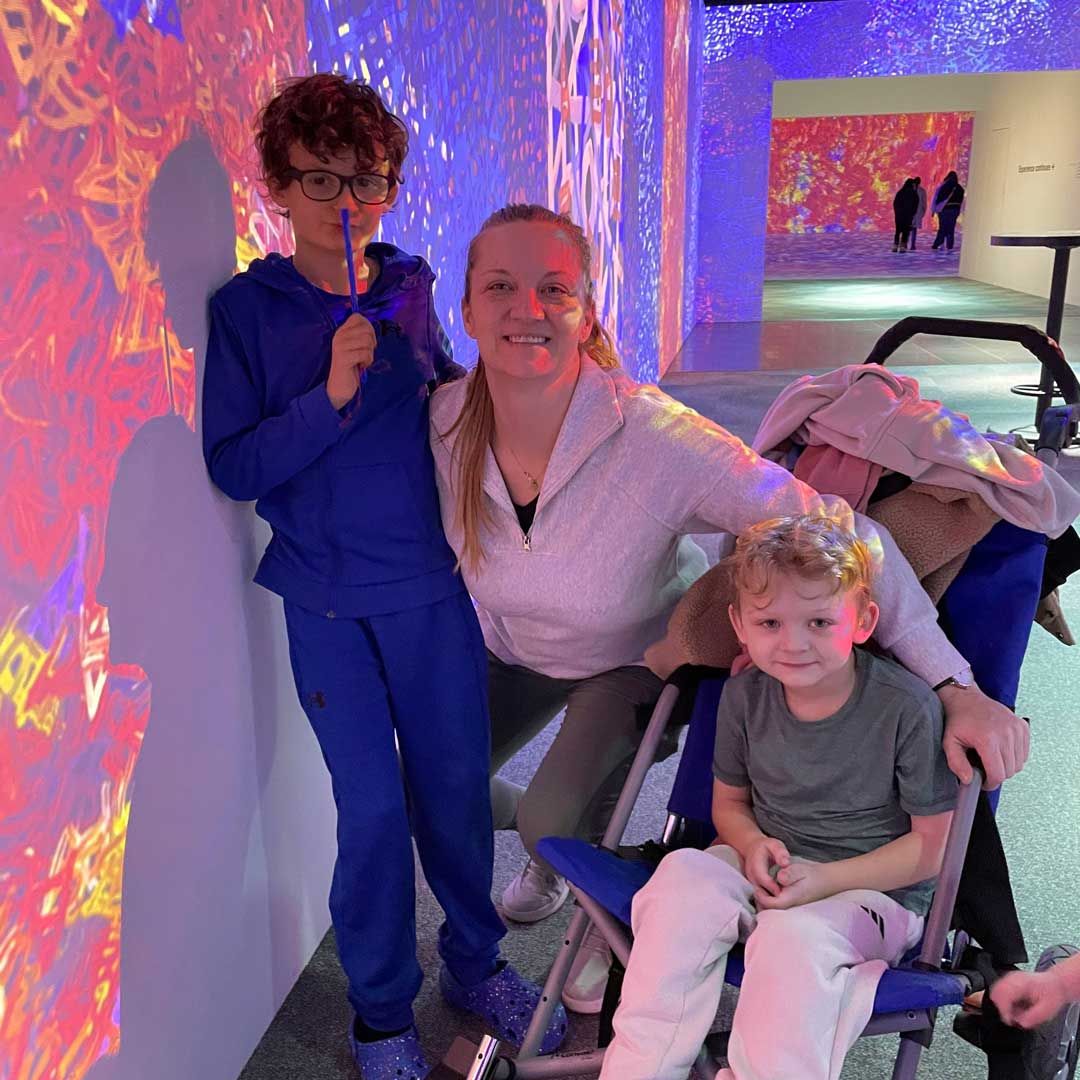 Kate Miller with her son Beau and younger child at a colorful immersive art exhibit