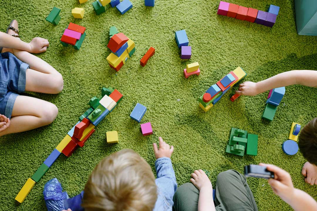Toddlers playing with colorful building blocks during a play-based therapy session